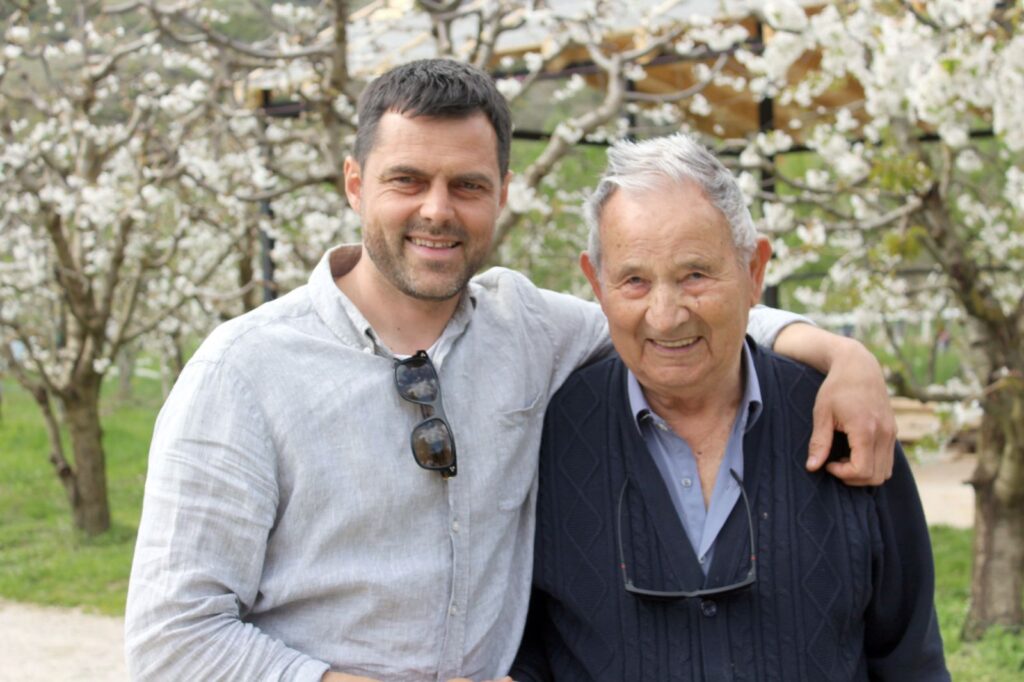 Home Orce Stojanoski with his grandfather Stojan among the blossoming orchard trees at Chateau Orman